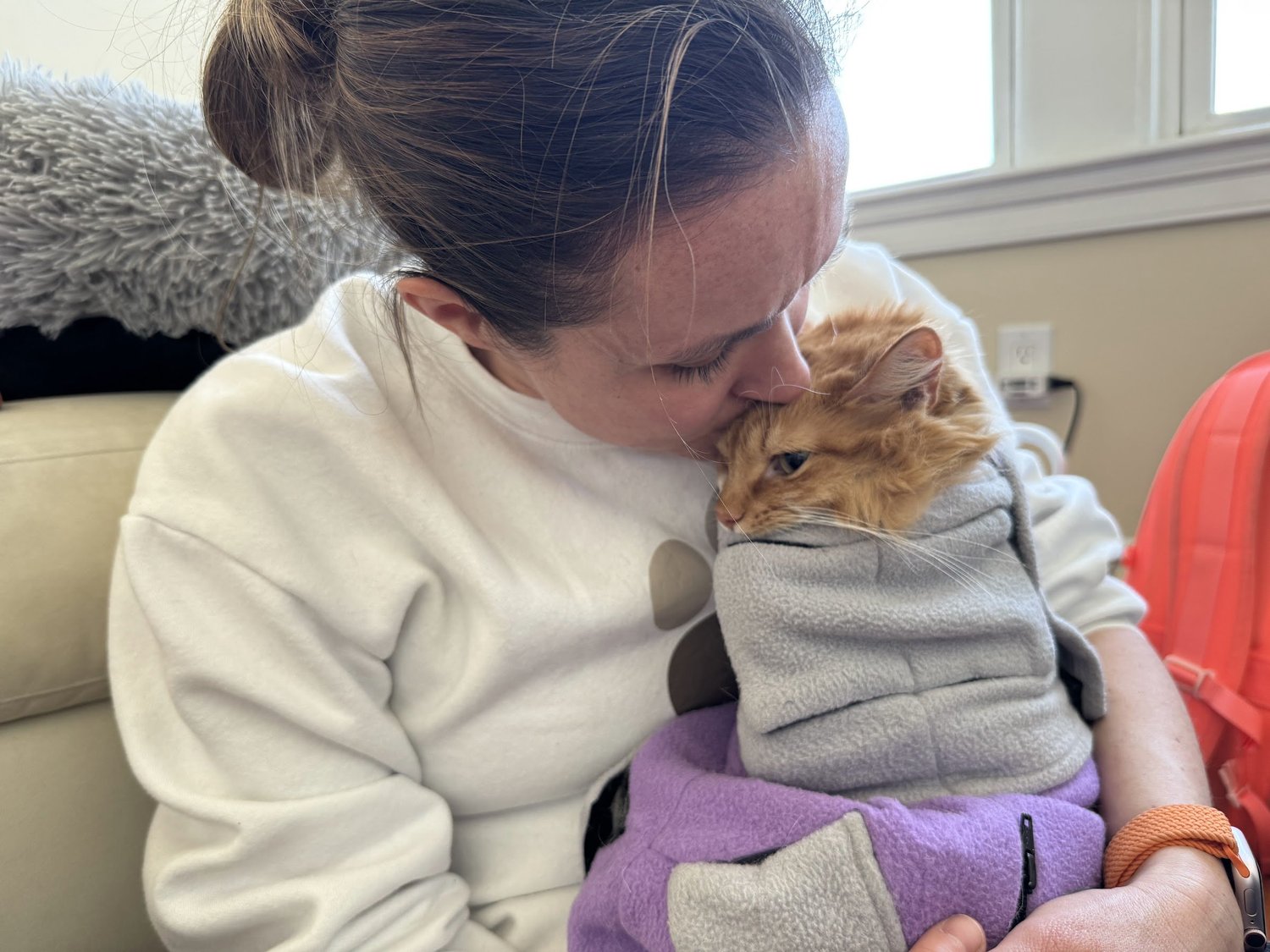 Dr. Dasha Perry gently holding a towel-wrapped cat during a home veterinary visit